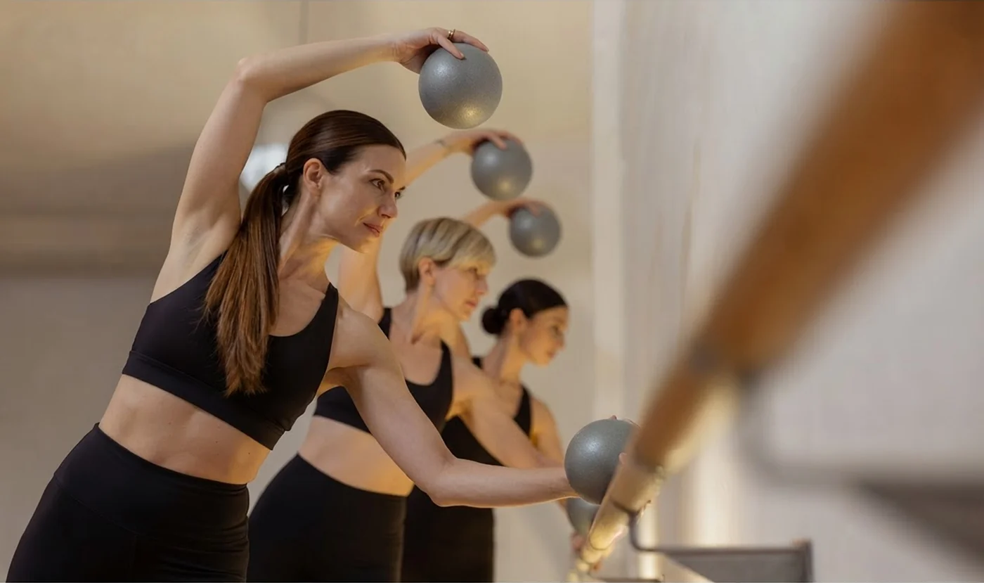 Alumna trabajando equilibrio en la barra durante una clase de barre en Bodylab