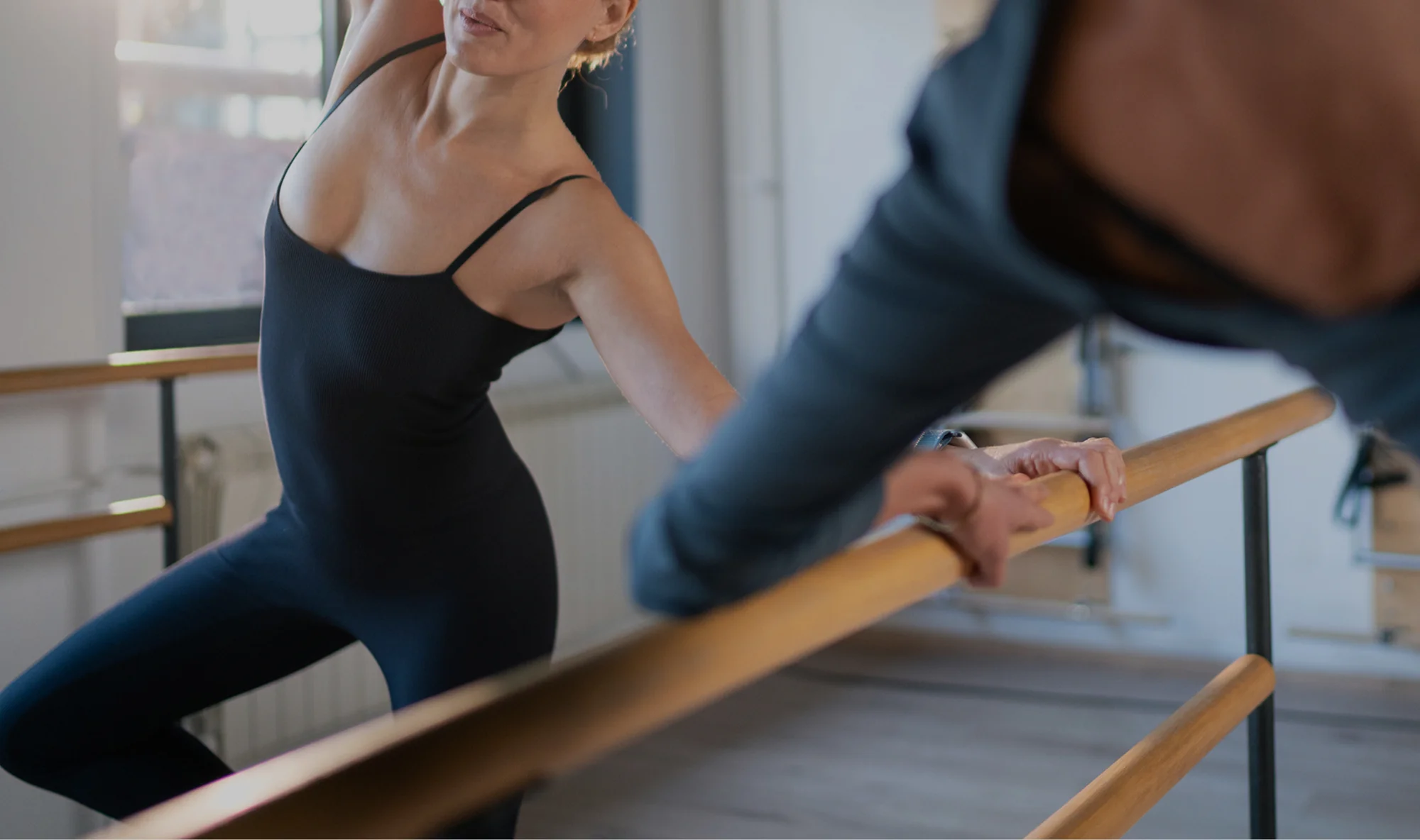 Alumna apoyada en la barra durante una clase de barre en Bodylab