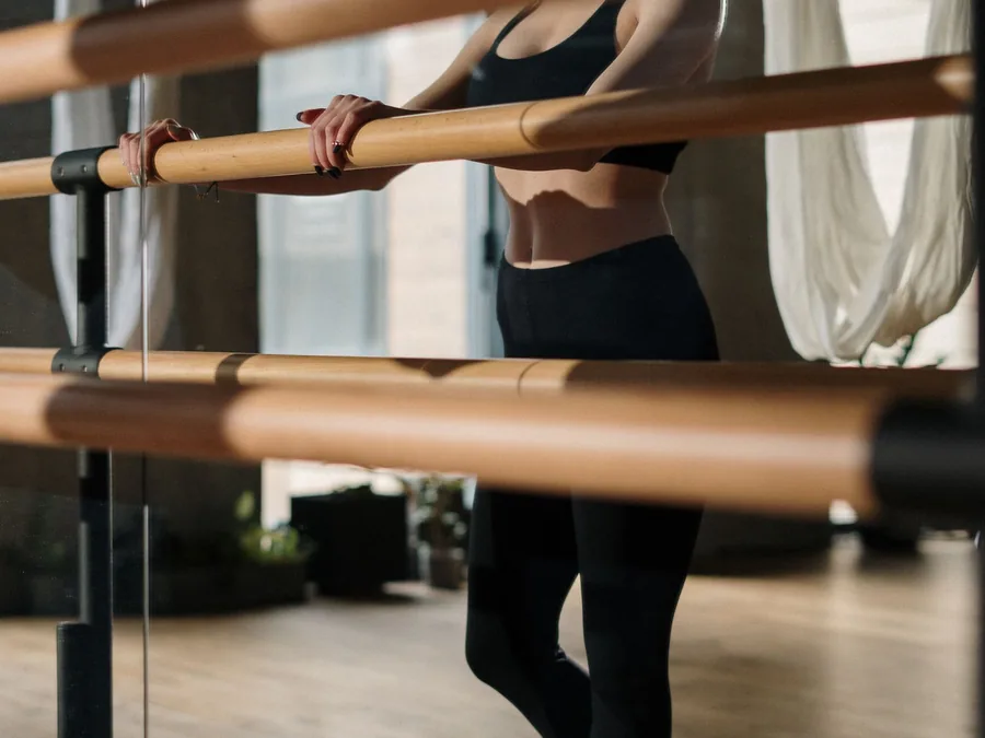 Alumna apoyada en la barra durante una clase de barre en Bodylab