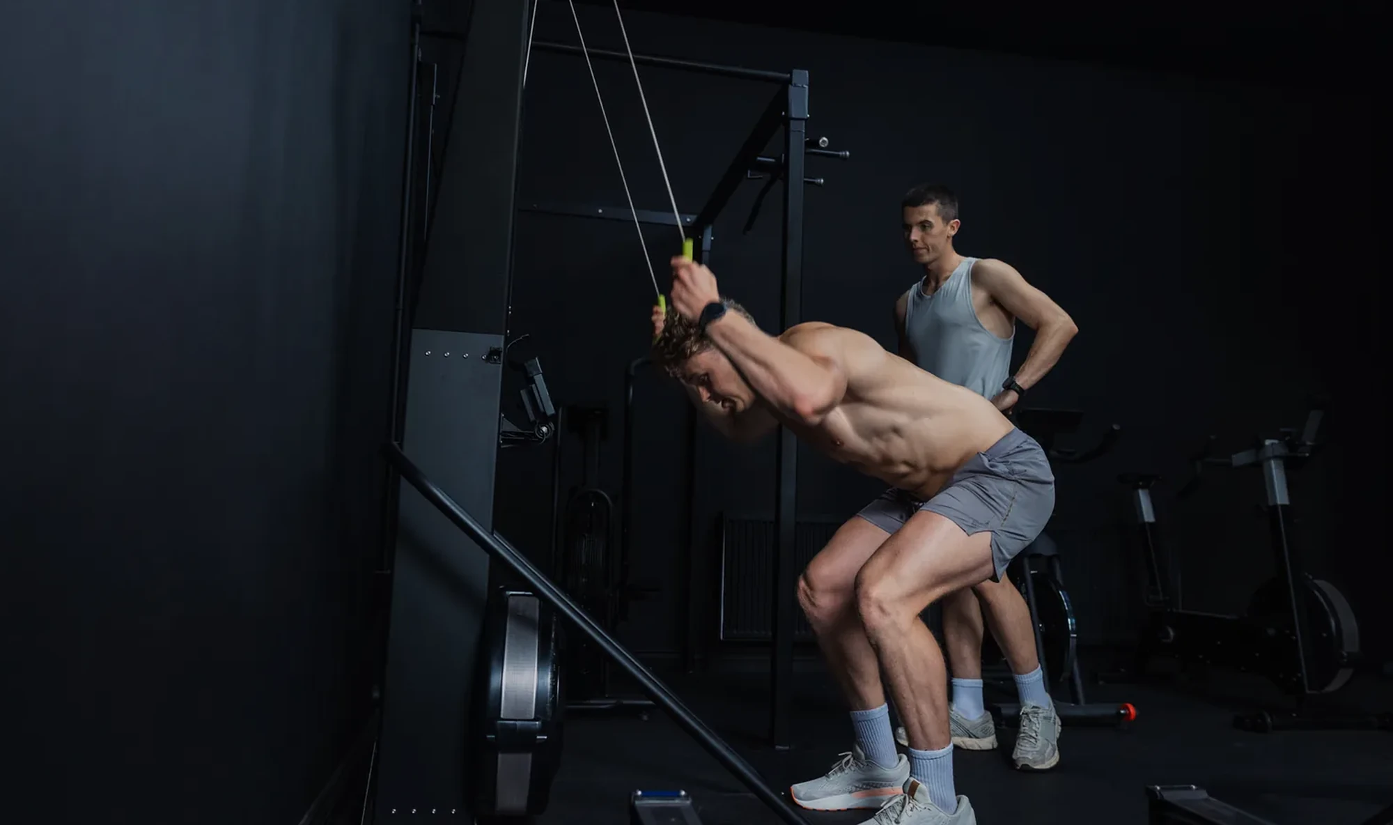 Un alumno realiza un ejercicio de tracción con cuerdas mientras otra persona lo supervisa en un entrenamiento en grupo reducido en Bodylab, San Sebastián de los Reyes