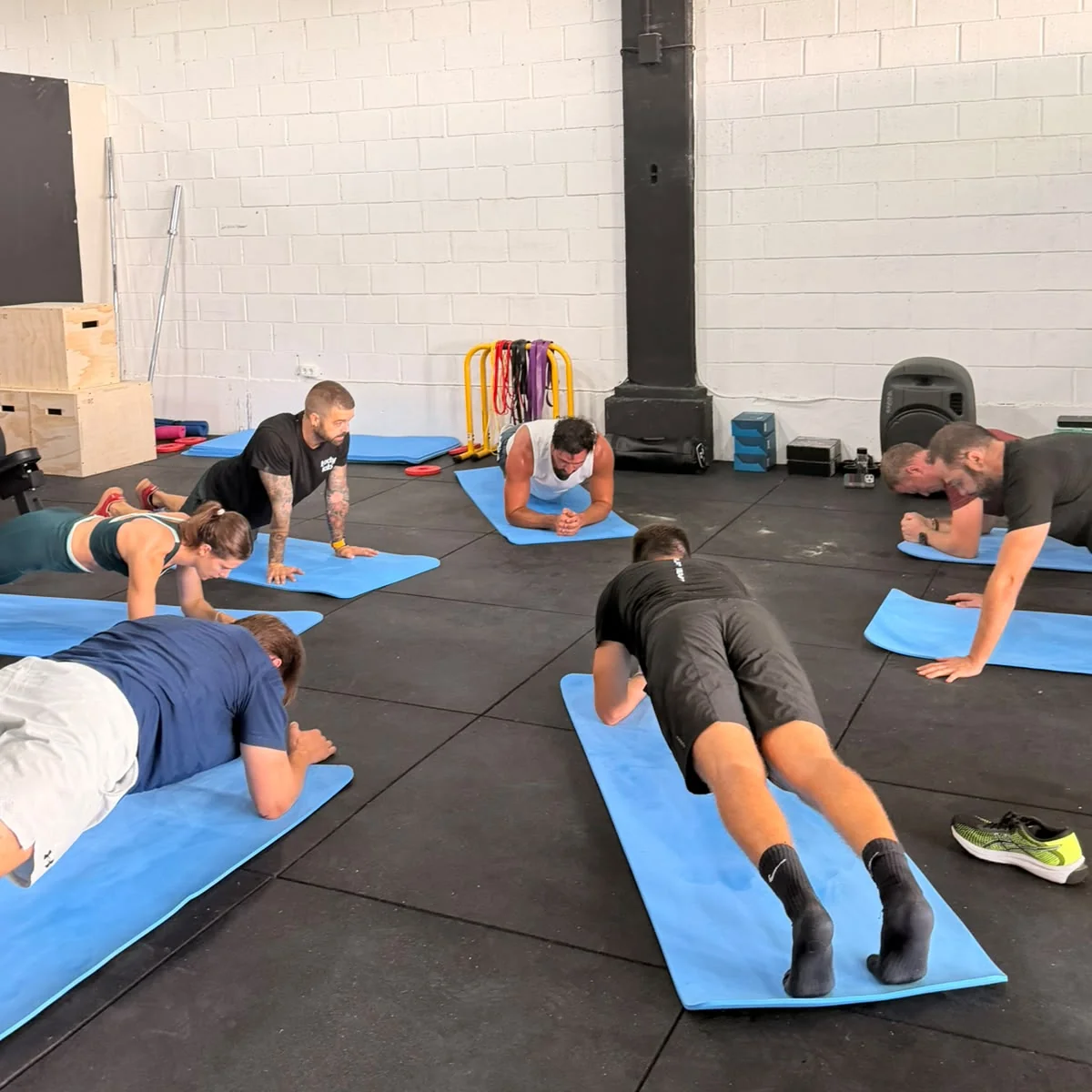 Grupo de alumnos haciendo planchas sobre esterillas durante una sesión de Entrenamiento Híbrido, San Sebastián de los Reyes