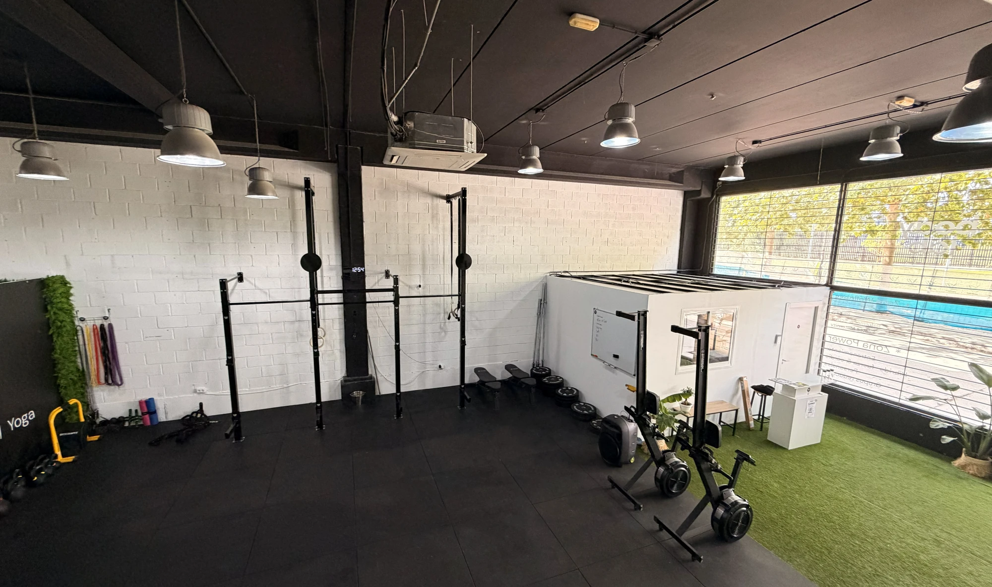 Vista general de la sala de entrenamiento de Bodylab con estructuras de dominadas, material de fuerza y suelo de césped artificial, San Sebastián de los Reyes